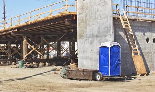 a clean and organized line of porta potties at a construction site, keeping workers content